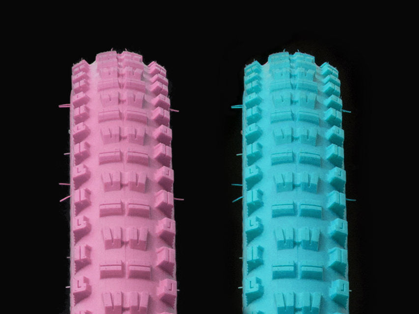 Two Versus All Mountain Bicycle Tires, one pink in color, one teal in color. 