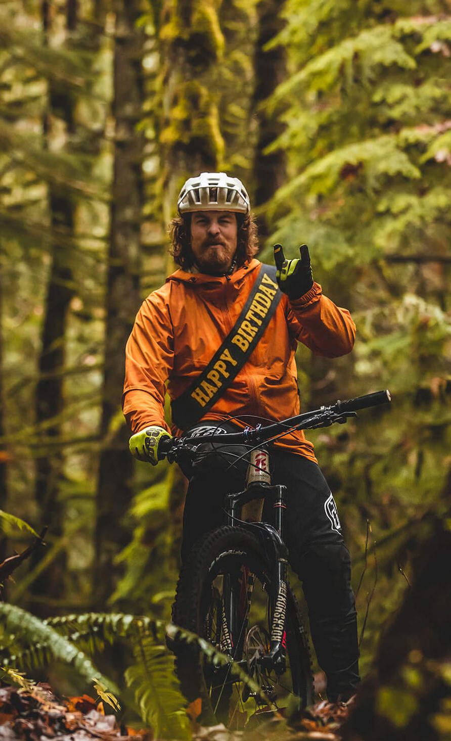 Person in an orange jacket with a bike in a forest