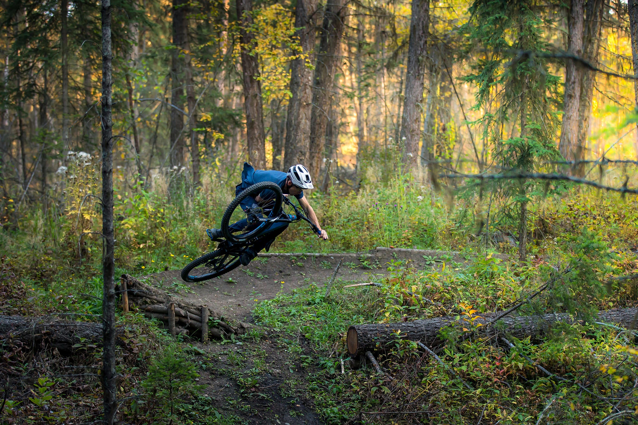 James Doerfling jumping his bicycle in the forest.